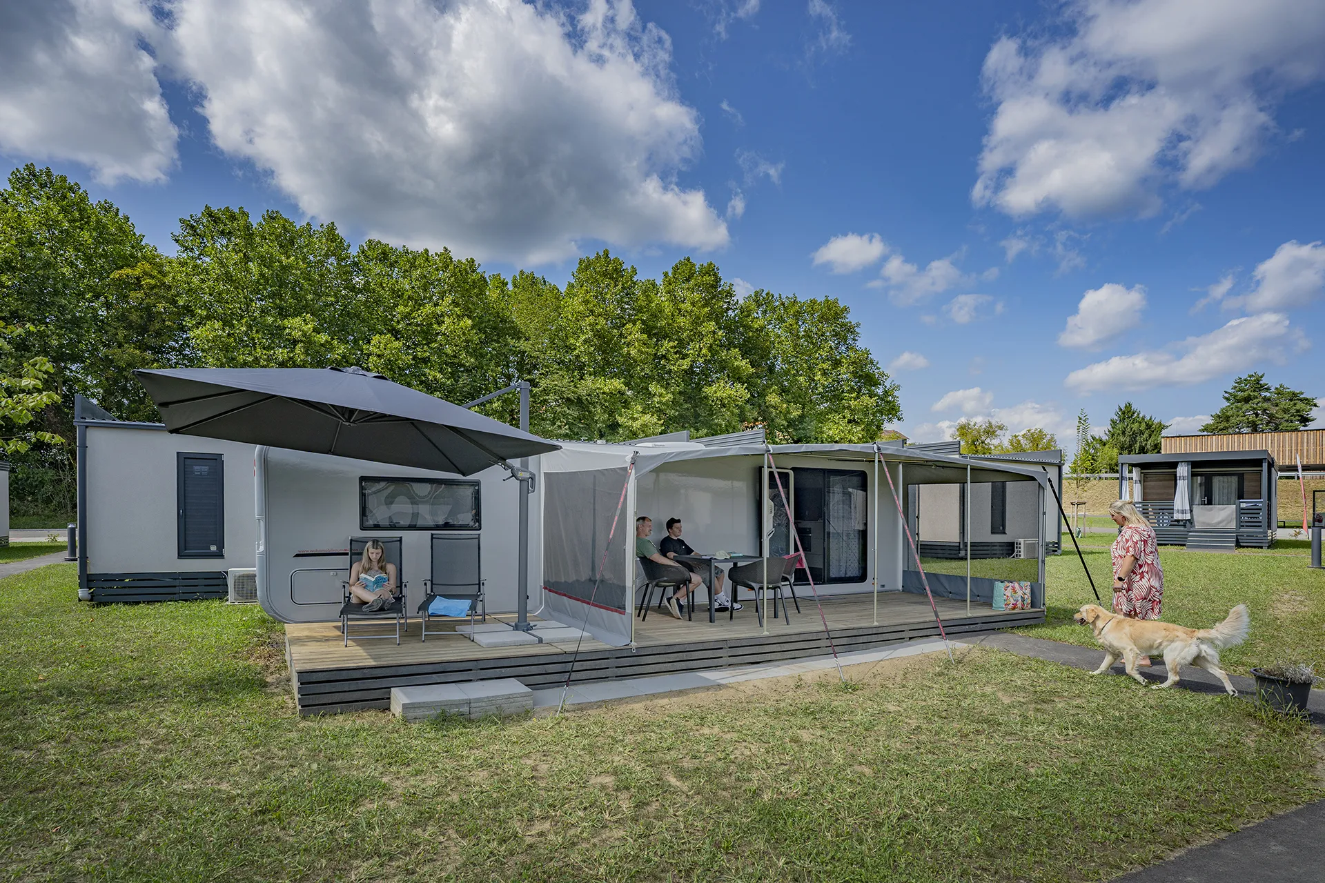 Ein Paar entspannt auf der großer Terrasse des modernen Wohnwagen Luxus Astella am Camping Resort Riegersburg