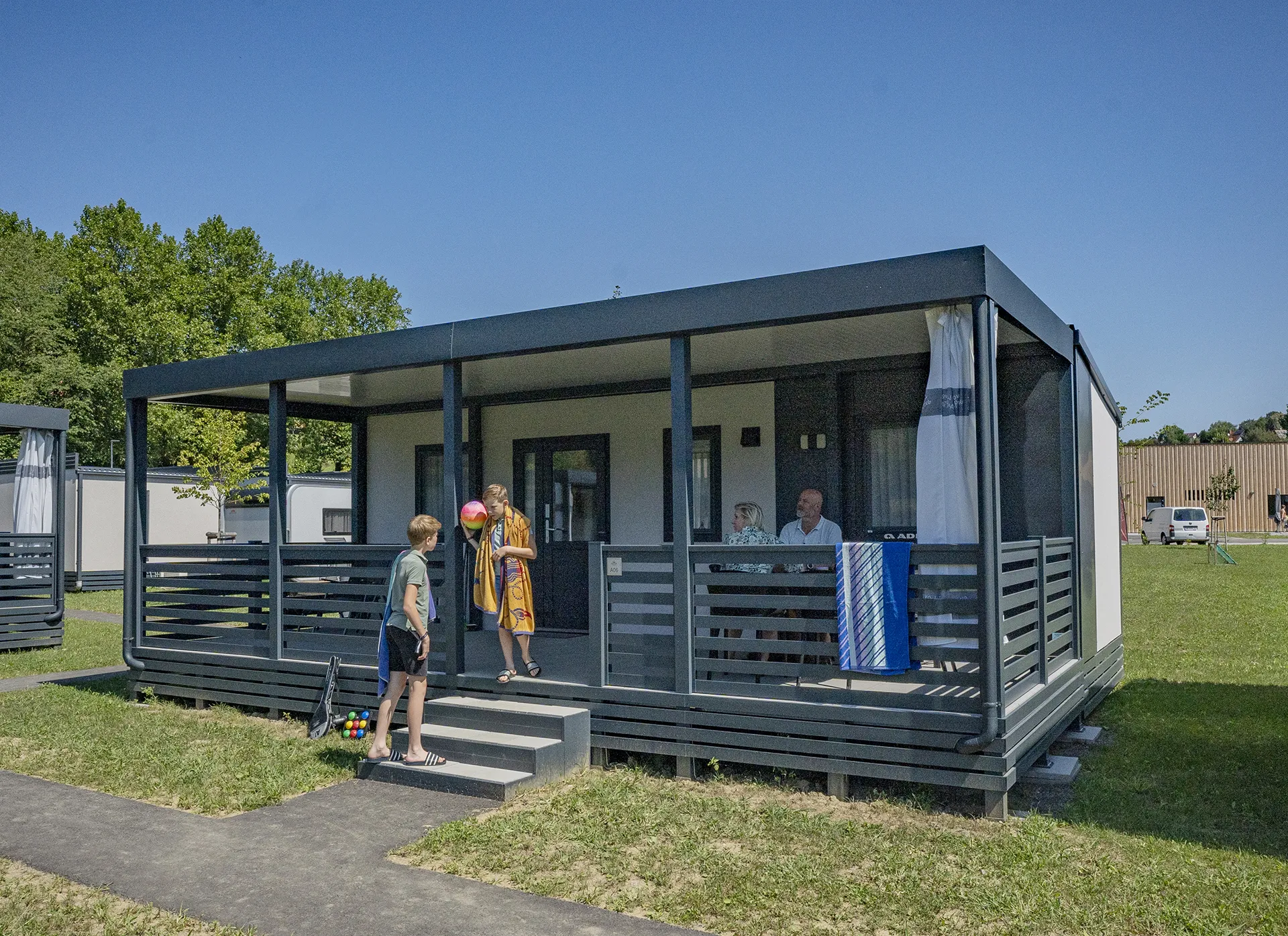 Familie auf der Terrasse vom modernen Mobilheim Premium A+ am Camping Resort Riegersburg.